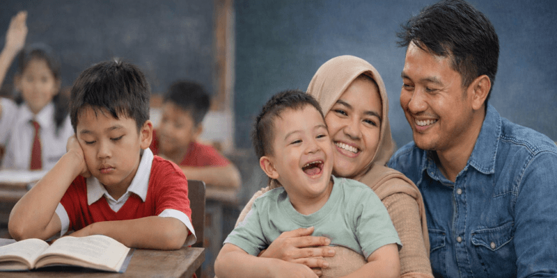 Anak Indonesia di kelas sekolah umum terlihat kesulitan belajar sementara orang tua memeluk anak berkebutuhan khusus dengan penuh perhatian.
