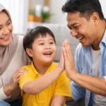 Anak berkebutuhan khusus wajah Jawa Indonesia sedang berinteraksi hangat dengan kedua orang tuanya di ruang tamu rumah yang nyaman dan terang.