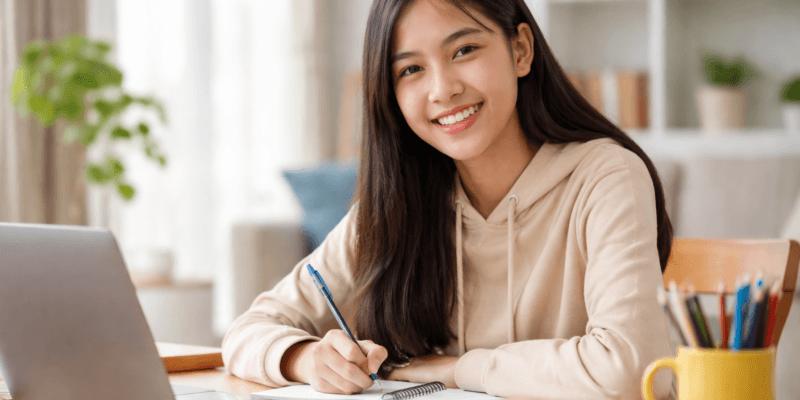 Anak introvert Jawa Indonesia terlihat bahagia belajar di rumah dengan suasana nyaman setelah terbebas dari perundungan di sekolah sebelumnya.