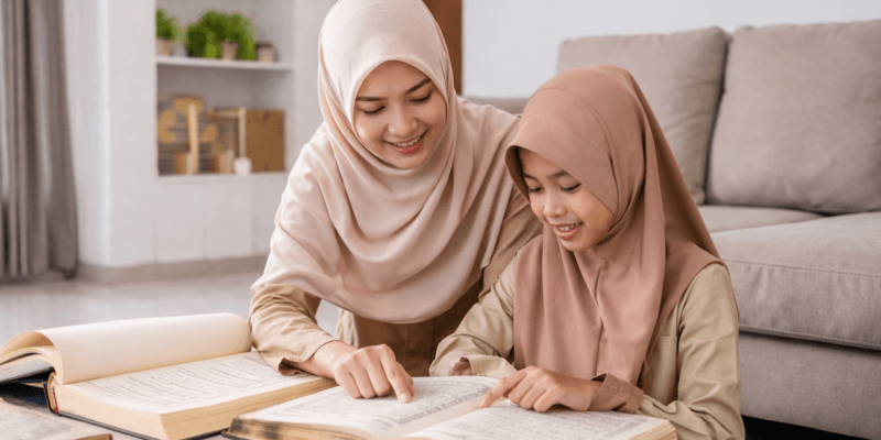 Guru wanita berhijab mengajar siswa perempuan membaca Al-Qur’an dalam suasana belajar homeschooling di rumah di Medan.